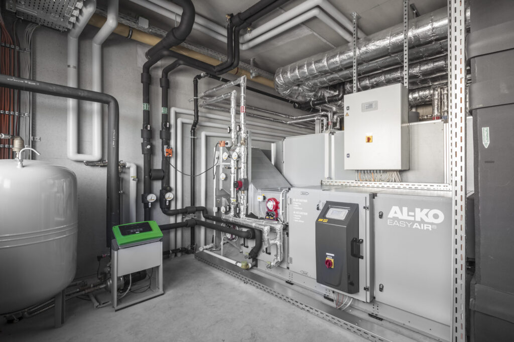 Technische Anlage mit AL-KO EASY AIR Gerät, Rohren, Ventilen und Steuerung in einem Raum mit grauem Boden und Wänden.